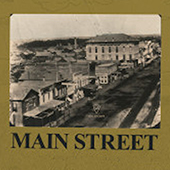 Black and white photo of an old main street town with dirt roads