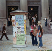 students look at a campus message board from the early 1980s