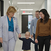 Ann Van Heest and Norman and his parents walking down a hall