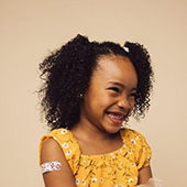 young girl smiling with bandaid on arm