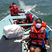 People in lifejackets on small boat delivering aid supplies
