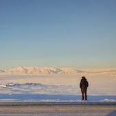 person standing on plain looking at snowy mountains