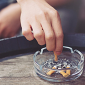 person putting out cigarette in ashtray