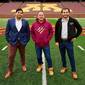 3 students of the law school stand on a stadium field