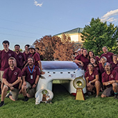 Solar vehicle team poses with winning car and trophy