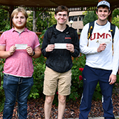 Robert Carlson, Alex Kozitka, and Jack Garmen pose with checks for $1,000