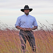 Marshall Johnson stands in field of wheat
