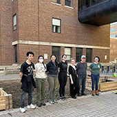 Students in front of garden pose for a photo