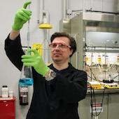 a lab man holds chemicals up