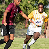 two soccer players compete for the ball 
