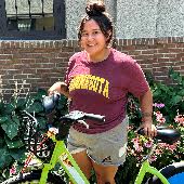 a student posing next to a green ride share bike