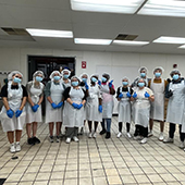 students wearing PPE work in a kitchen for a food bank