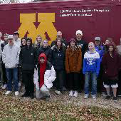 Morris Challenge Rural Youth Institute participants stand in front of a maroon and gold M vehicle