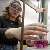 A student in lab goggles conducts an experiment