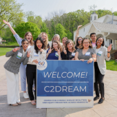Tarissa and coworkers hold a sign reading Welcome! C2DREAM