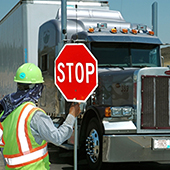 Work-zone flagger holding up a stop sign to a large truck