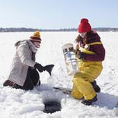 Alia Benedict and another student take a water sample through the ice