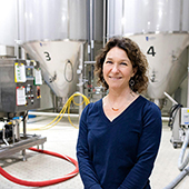 Paige Novak among brewing equipment at Fulton Brewing