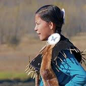 An Indigenous woman in traditional dress dancing
