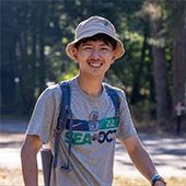 Yusuke Matsuda wearing a backpack and hiking in a wooded area