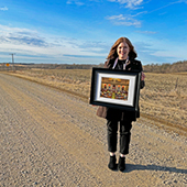 Ashby Mayor Amy Johnson stands on a gravel road holding a photo she took at the state capitol
