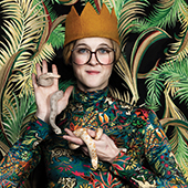 Emily Roberts wears a felt crown and holds a small snake with a faux, jungle-like background