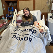 Kailyn Dewey in hospital bed with blanket reading donor