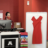 A red dress hangs from a shite background during a presentation 