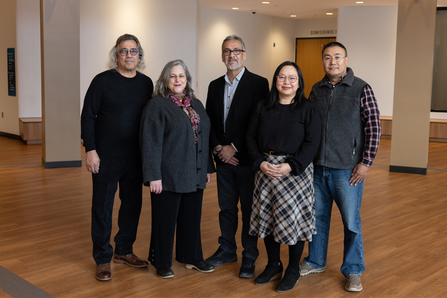 Five people stand together for a group photo in a lobby.