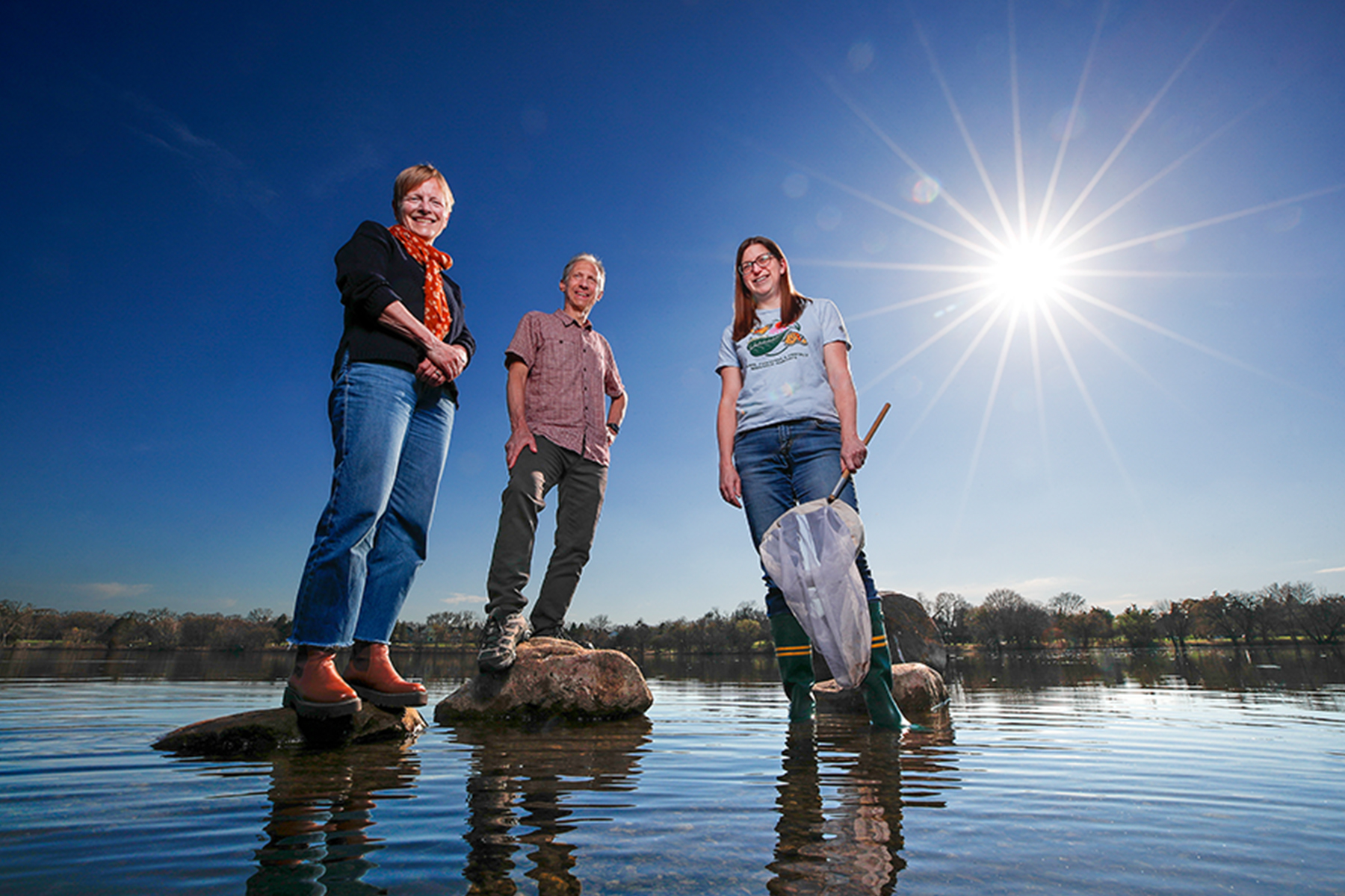  Sarah Hobbie, Jacques Finlay and Emilie Snell-Rood stand on rocks on Lake Como.