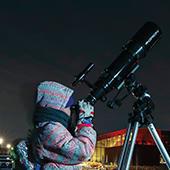 young person looking through telescope